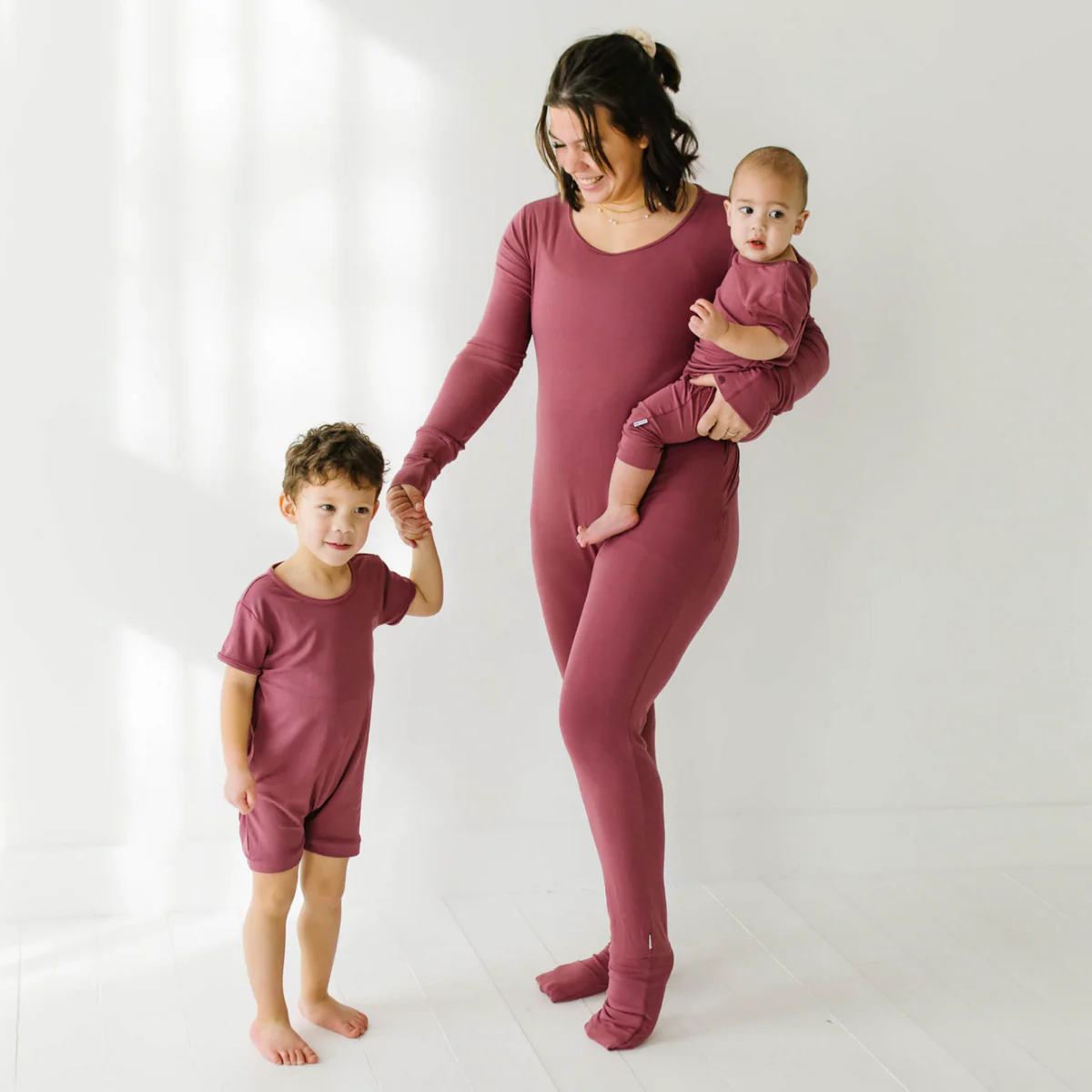 Mother, son and baby wear matching rompers in burgundy